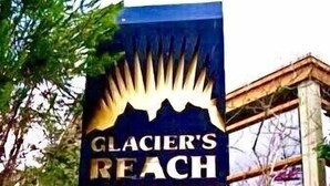 Un letrero de madera con el texto 'Glacier's Reach 4388 Northlands Boulevard' y un gráfico de una montaña.