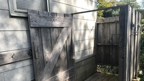 A wooden gate leading to a deck area with a concrete wall and a window. - Secluded 1 Br Cottage on the Lake, Close to Ditch with OS Shower & Fabulous Yard (Montauk)