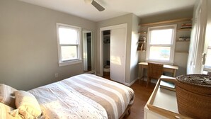 A bedroom with a bed, a desk, and a chair. There are two windows and a ceiling fan. - Secluded 1 Br Cottage on the Lake, Close to Ditch with OS Shower & Fabulous Yard (Montauk)