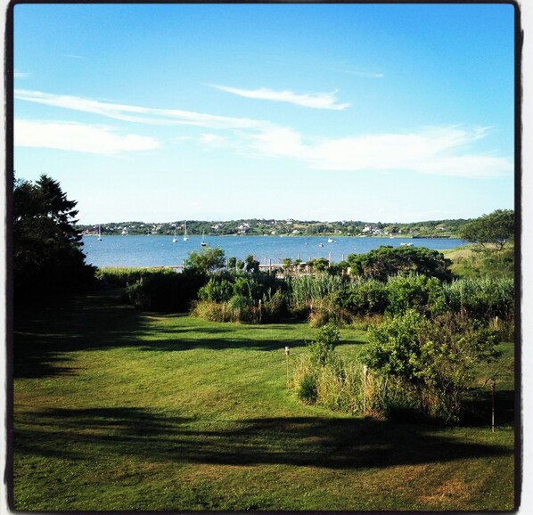 A grassy area with a view of a lake and sailboats.