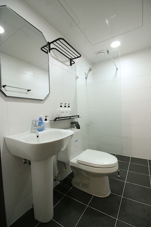 A modern bathroom with a white sink, a toilet, and a shower.