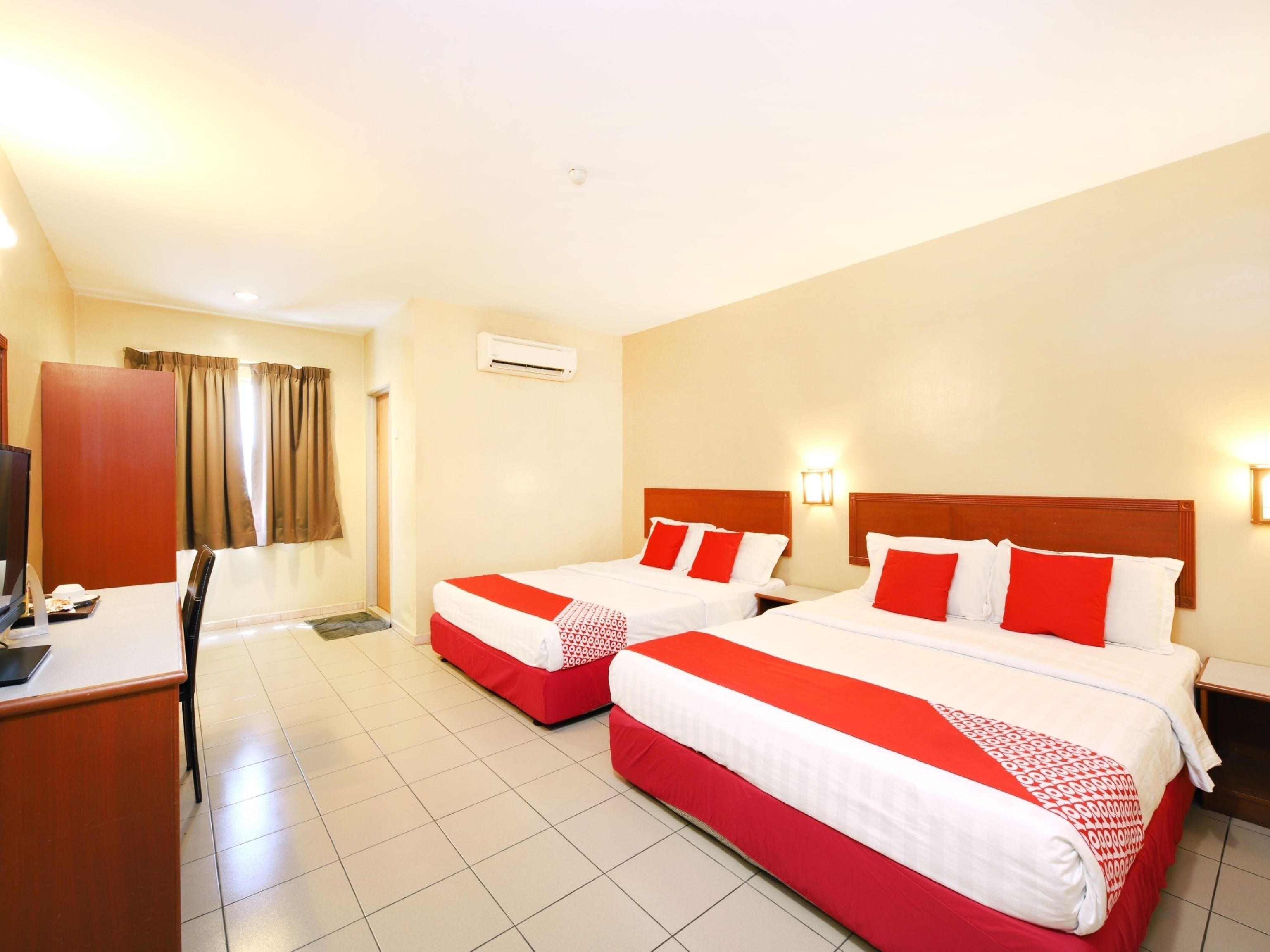 A hotel room with two beds, a desk, and a TV.