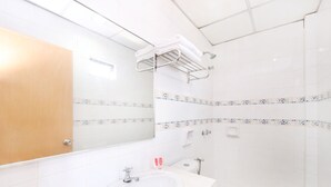 A modern bathroom with a large mirror, white sink, toilet, and shower area.