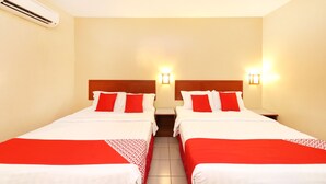 A hotel room with two beds, each with red and white bedding, and two wall-mounted nightstands.