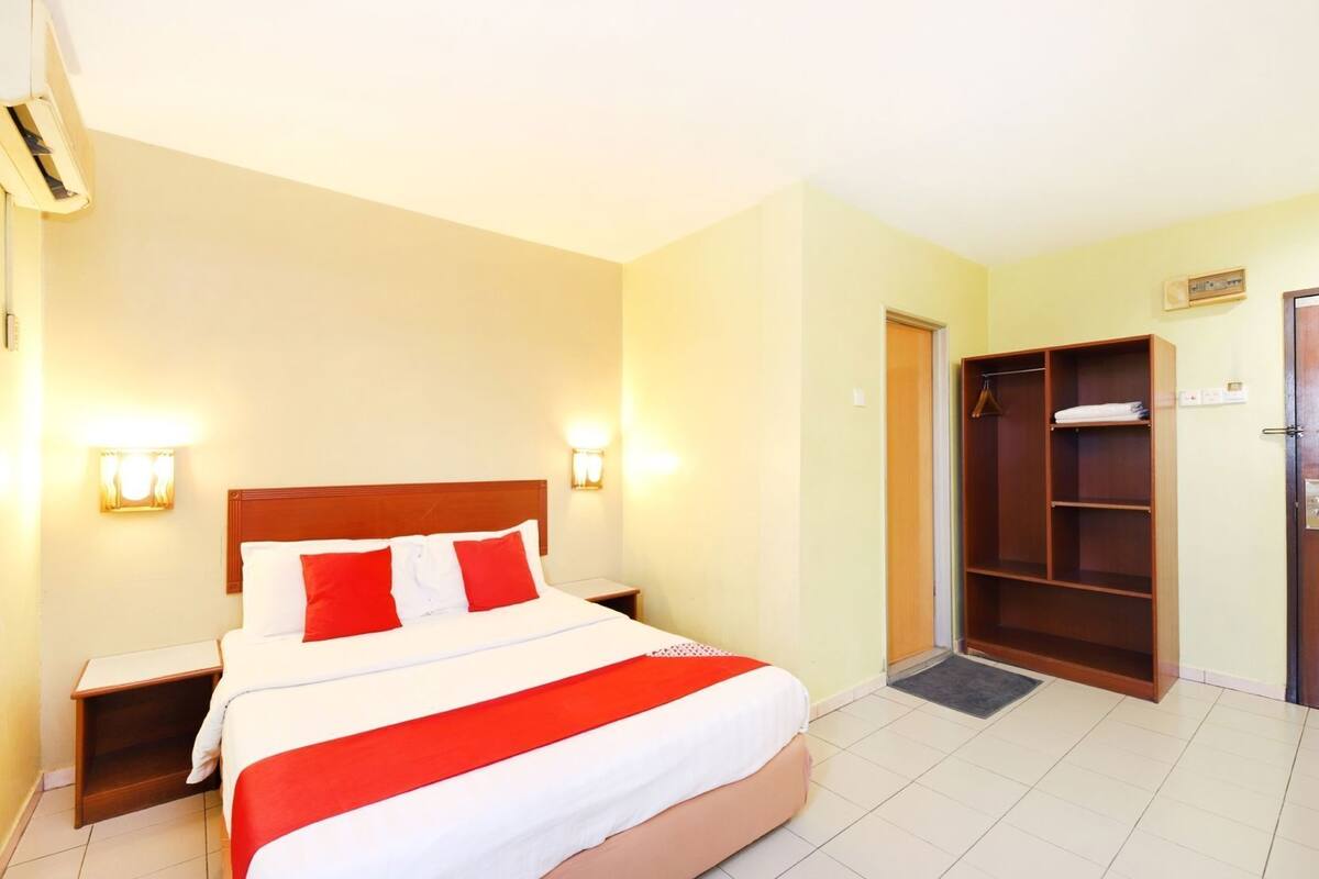 A hotel room with a bed, nightstands, a wardrobe, and wall-mounted lights.