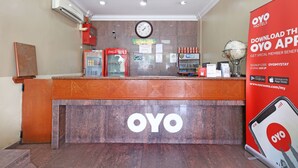 A reception desk with a clock, a Coca-Cola refrigerator, a Wi-Fi sign, and a promotional poster for the OYO app.