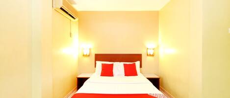 A hotel room with a bed, two bedside tables, and wall-mounted lights.