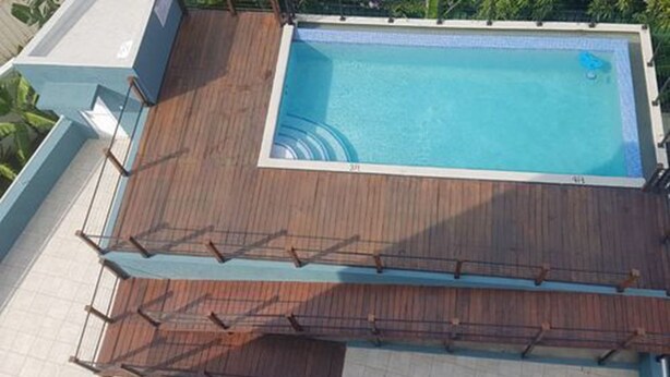 Una piscina con cubierta de madera, rodeada por una zona de baldosas blancas.