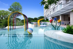 A swimming pool with colorful slides and inflatable toys, surrounded by a building with balconies. - Centre Point Prime Hotel Pattaya (Pattaya)