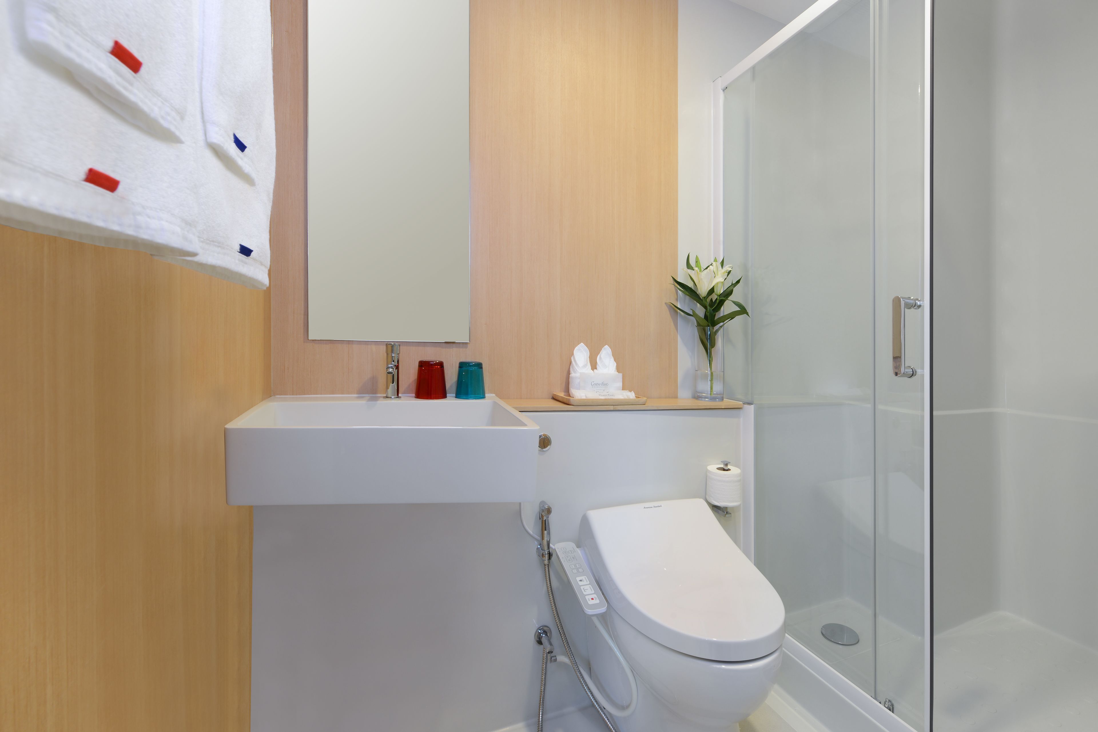 Et moderne badeværelse med en hvid vask, toilet og en bruseniche med glasvægge.