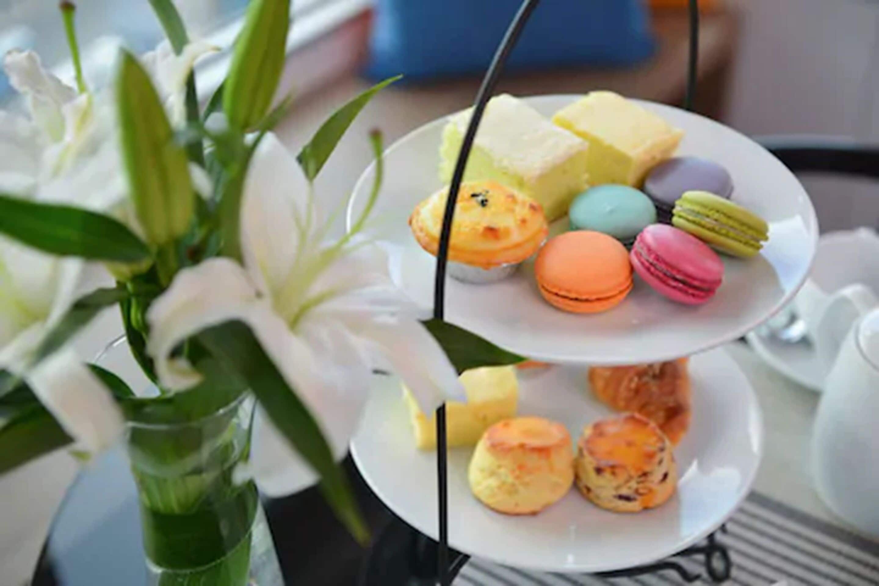 Een taartbord met drie niveaus, bedekt met macarons en gebak.