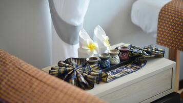 A neatly arranged tray with a patterned cloth, two white flowers, and small decorative items on a bedside table in a hotel room.