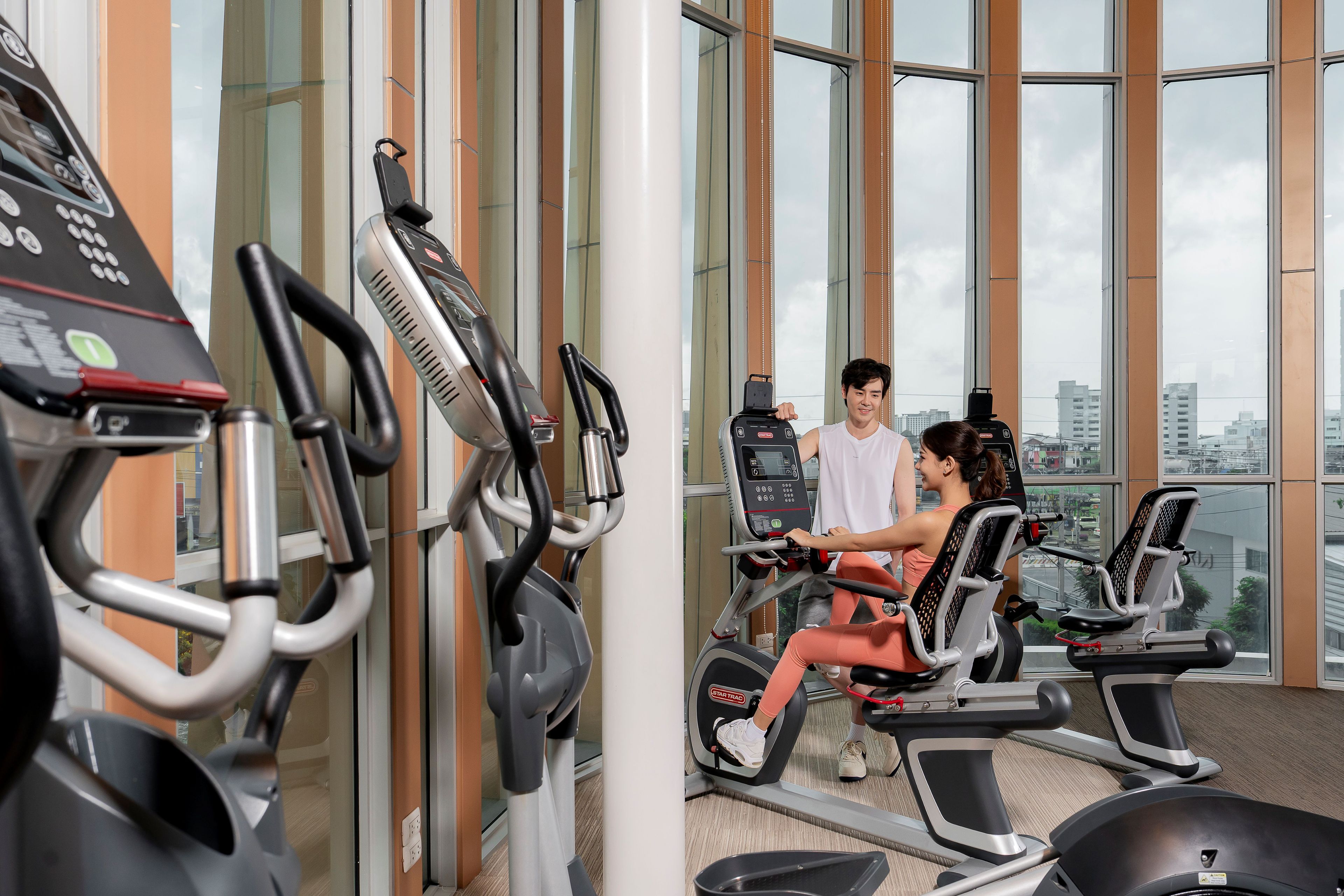 A gym with exercise equipment, large windows, and a view of buildings.