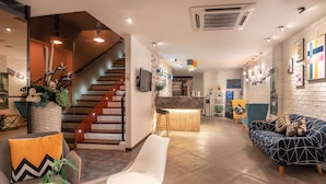 A modern interior with a staircase, seating area, and a bar. - Apple Hotel Times Square (George Town)