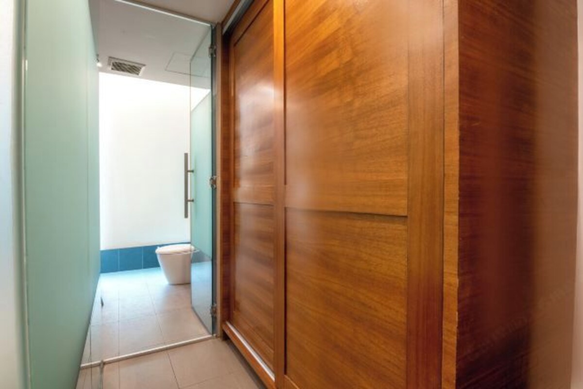 Een gang met een houten garderobe en een uitzicht op een badkamer met toilet.