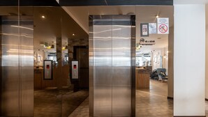A modern elevator with a metallic finish, a no smoking sign, and a digital display. - Apple Hotel Times Square (George Town)