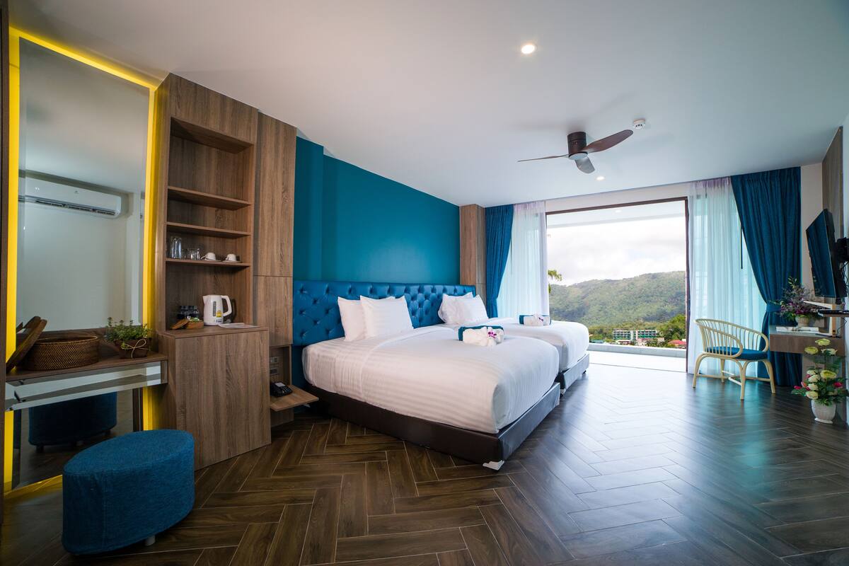 A modern hotel room with a large bed, a desk, and a balcony with a view.