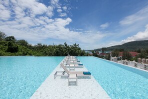 A long, clear swimming pool with lounge chairs and a white deck extending into the water. - Oceana Resort Phuket (Kamala)