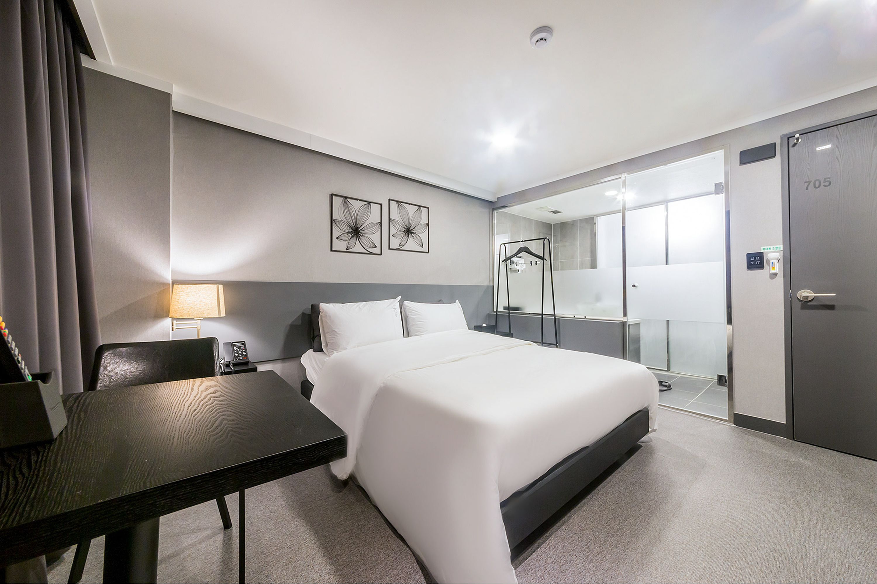 Een hotelkamer met een bed, een bureau, een stoel, een lamp, een spiegel en een kledingkast.