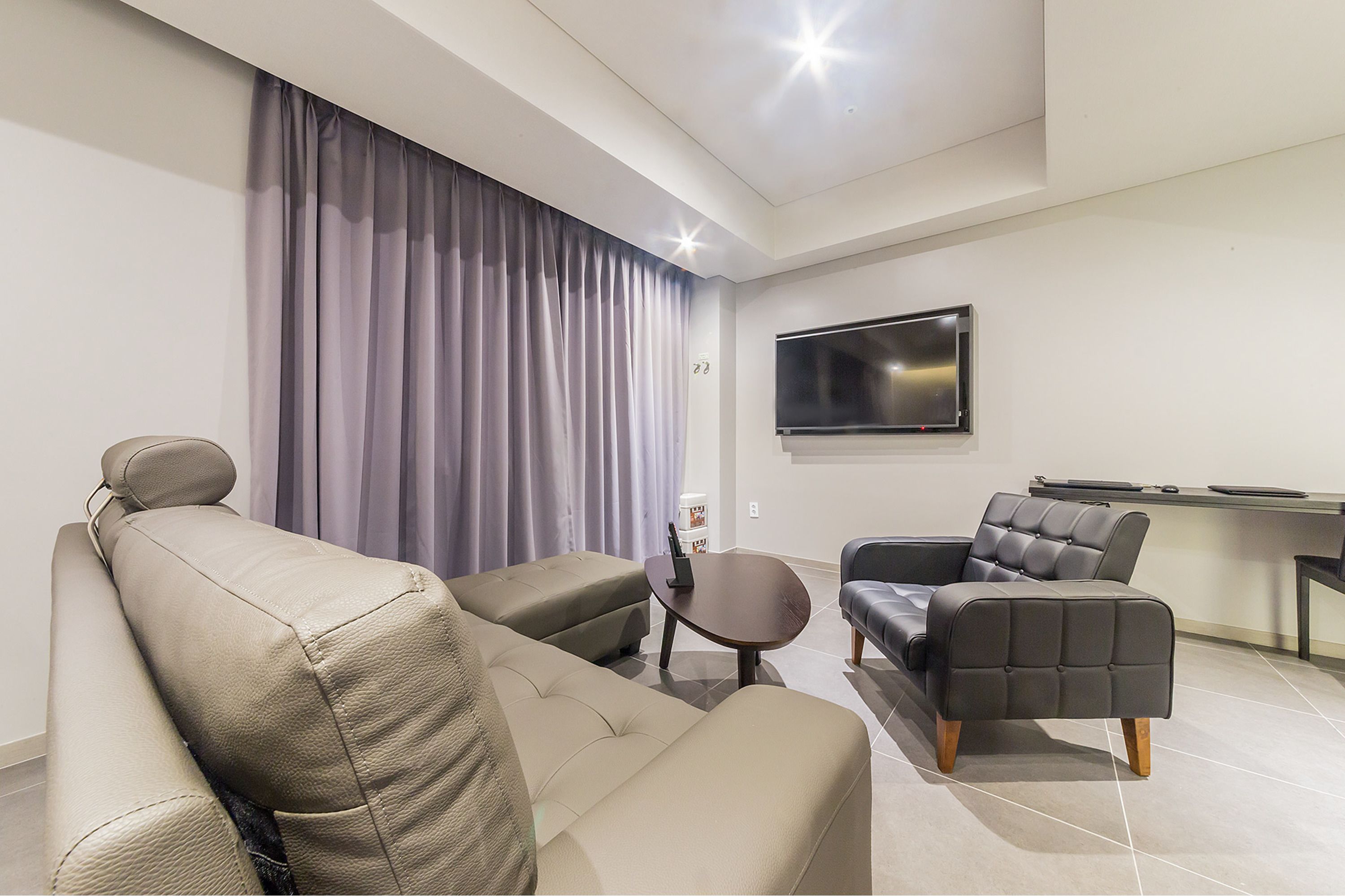 A modern living room with a sofa, armchair, and a small table.