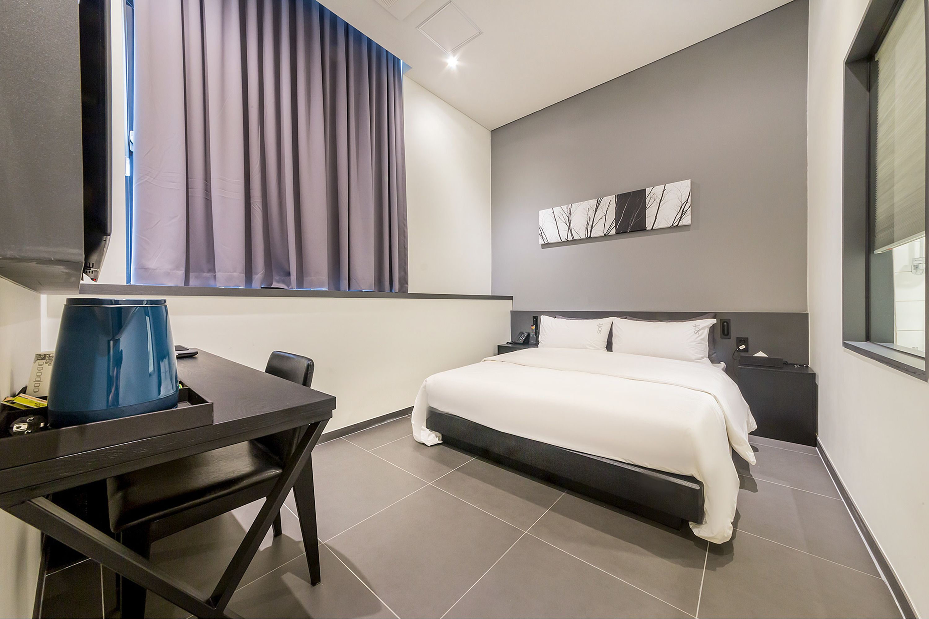 A modern hotel room with a bed, a desk, and a chair.