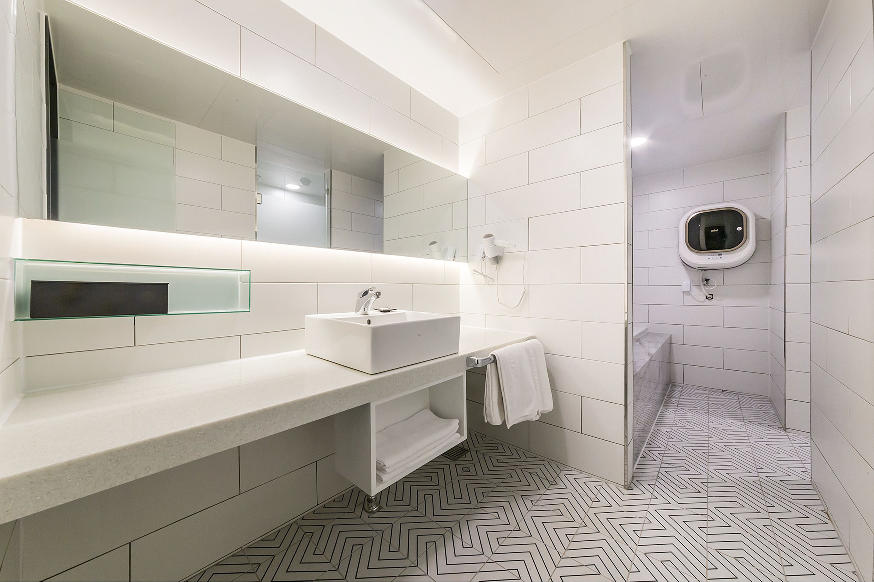 A modern bathroom with a white sink, mirror, and shower.