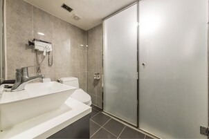 A modern bathroom with a white sink, a toilet, and a glass shower enclosure.