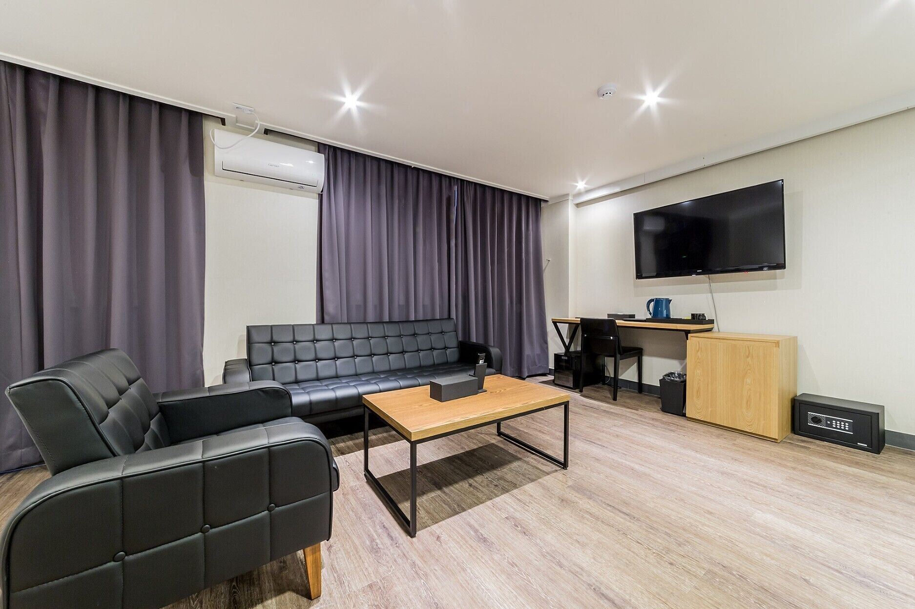 A modern living room with a sofa, a coffee table, a TV, and a desk.