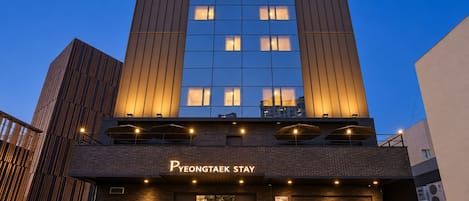 Un hotel moderno con fachada oscura, ventanas amplias y un letrero que dice 'PEONTAEK STAY'.