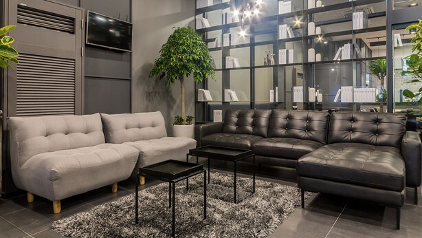A modern living room with a grey sofa, a black leather sofa, a coffee table, and a bookshelf filled with books and decorative items. - Pyeongtaek Stay Hotel (Pyeongtaek)