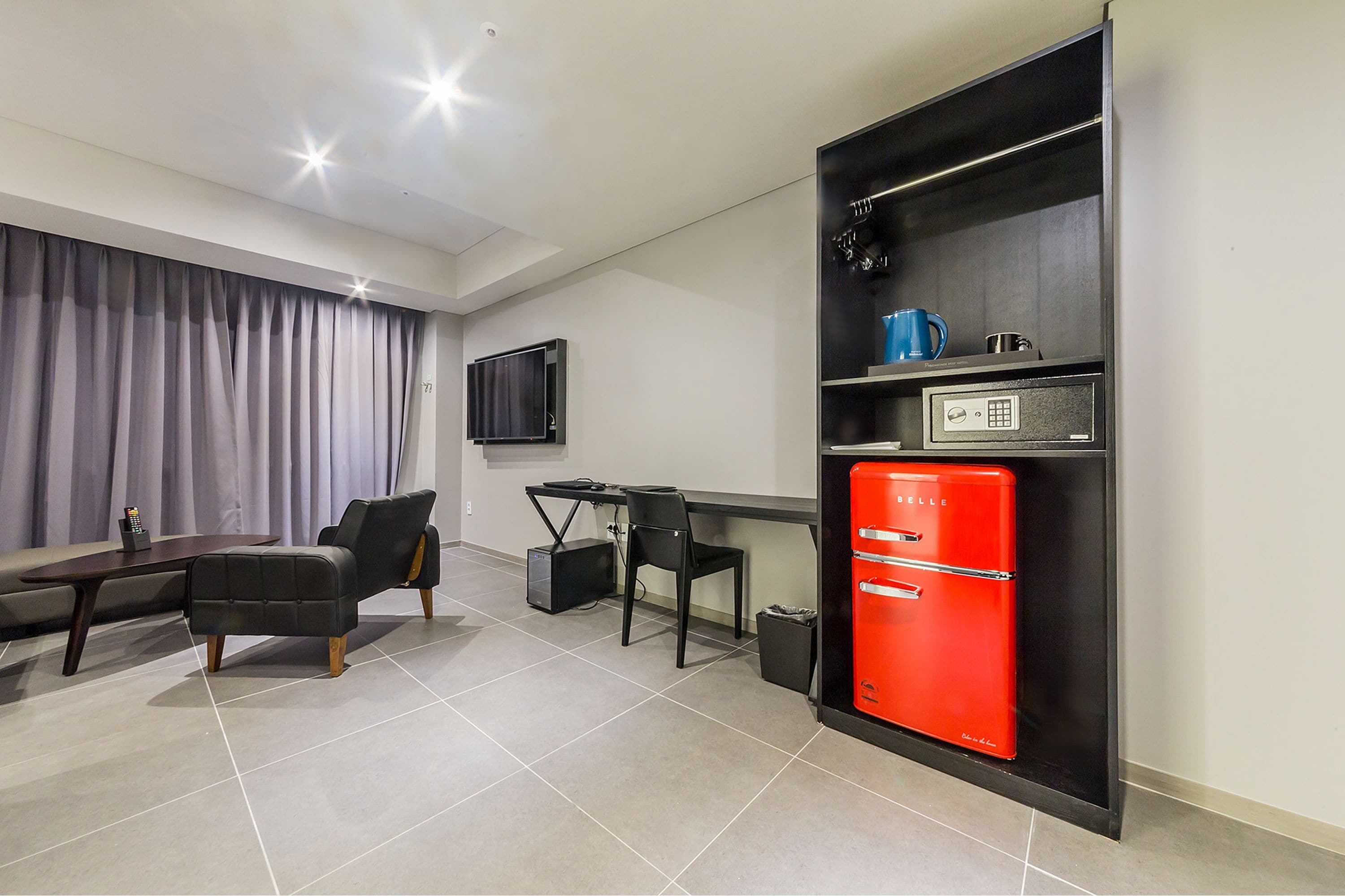 A modern living room with a sofa, a dining table, and a red refrigerator.