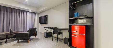 A modern living room with a sofa, a dining table, and a red refrigerator.