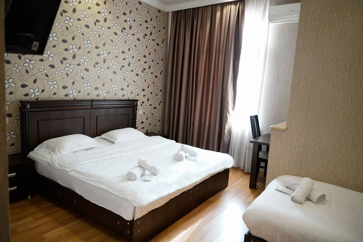Une chambre d’hôtel avec un lit en bois, une petite table de chevet et une chaise.