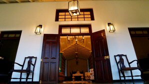 A traditional entrance with wooden doors, a chandelier, and wall-mounted lanterns. - Thompson Manor - A Luxury Villa in Galle (Akmeemana)