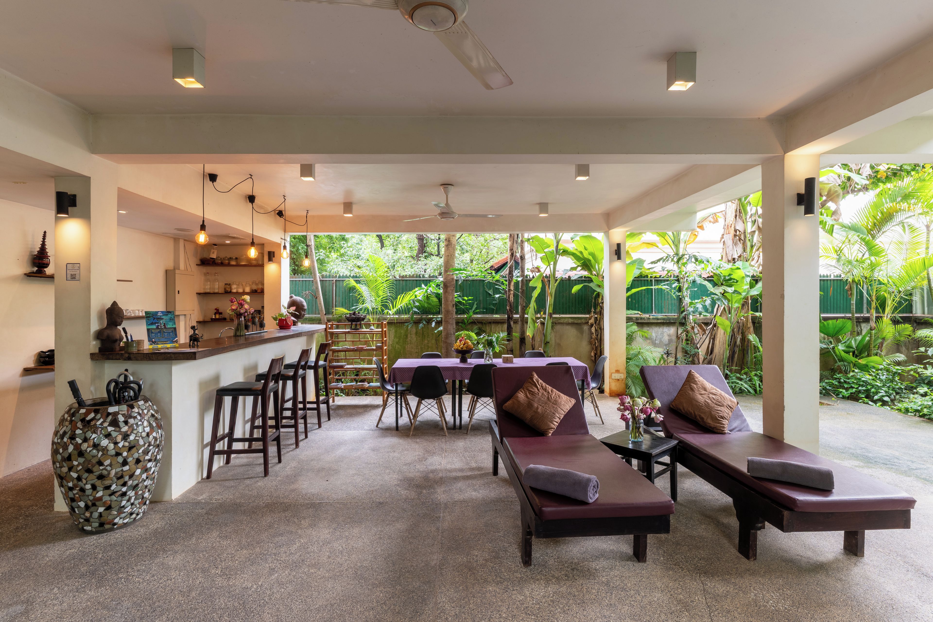 A spacious outdoor area with a bar, seating, and a view of lush greenery.