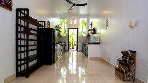 A hallway with a ceiling fan, a door leading outside, and a shelf with items on the left. - Enkosa Modern Villa (Siem Reap)