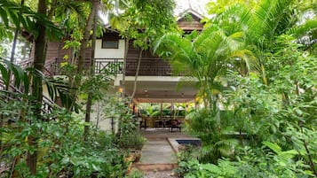 A two-story building with a balcony, surrounded by dense tropical vegetation.