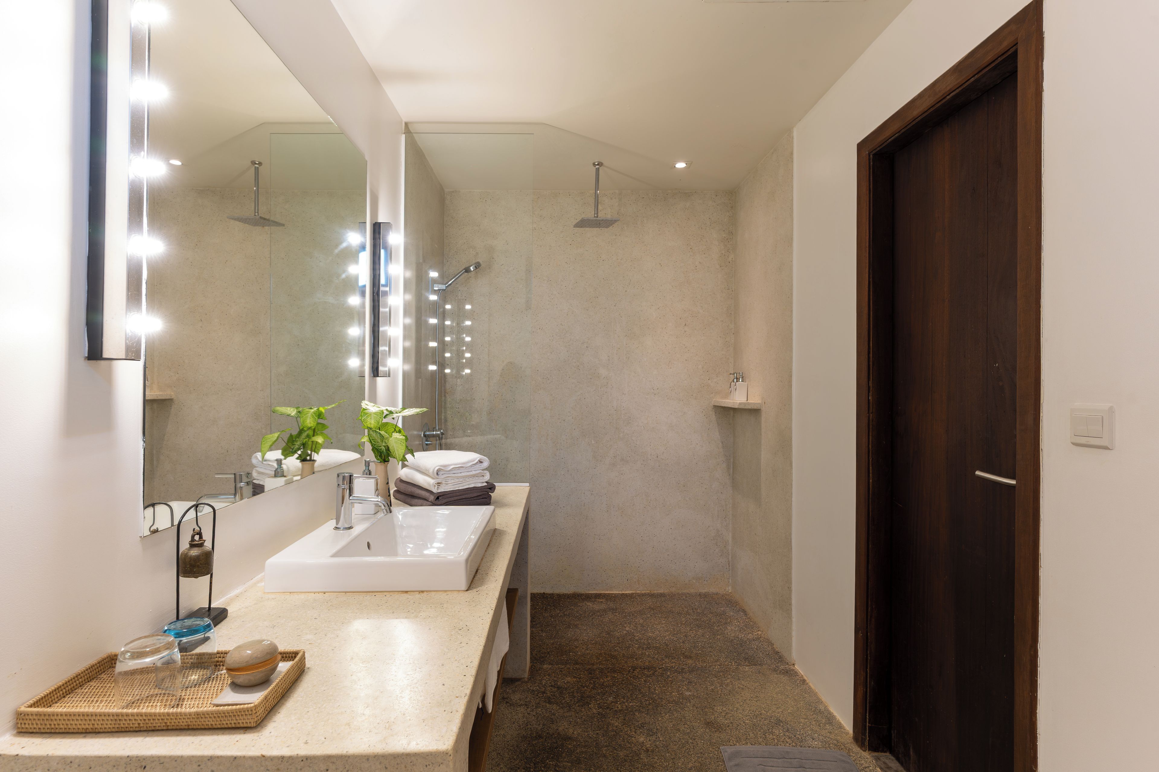 Un baño moderno con un espejo grande, tocador y ducha.