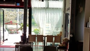 A cozy indoor space with a round table and chairs, a sofa, and a large window with curtains. - Inje Tourist Hotel (Inje)