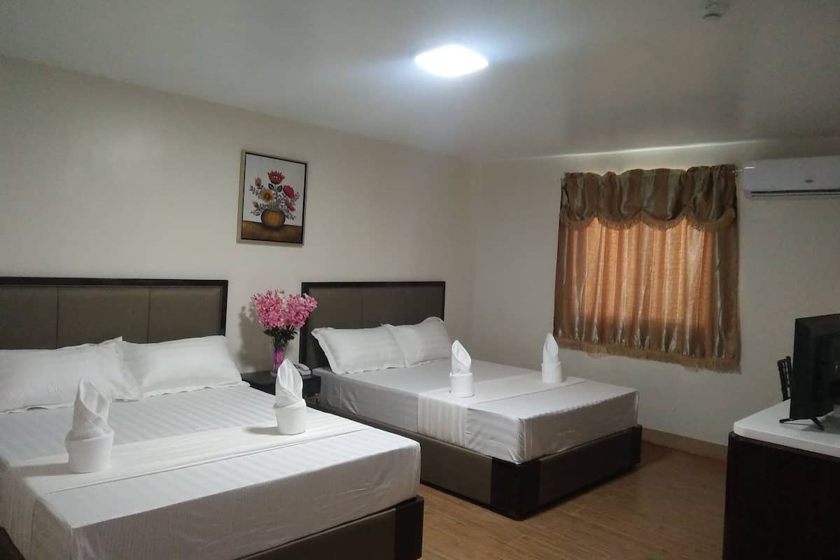 A hotel room with two beds, a painting on the wall, a window with curtains, and an air conditioning unit.