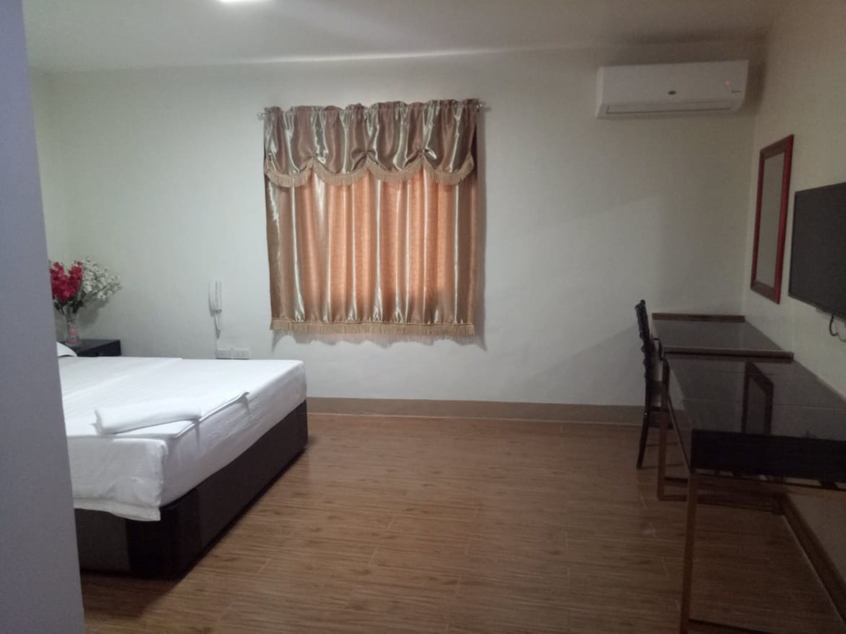 A hotel room with a bed, a desk, and a TV.