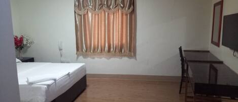 Una habitación de hotel con cama, escritorio y televisión.