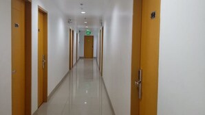 A long, narrow hallway with doors on both sides, a tiled floor, and a ceiling with recessed lighting. - Meaco Royal Hotel - Batangas City (Batangas City)