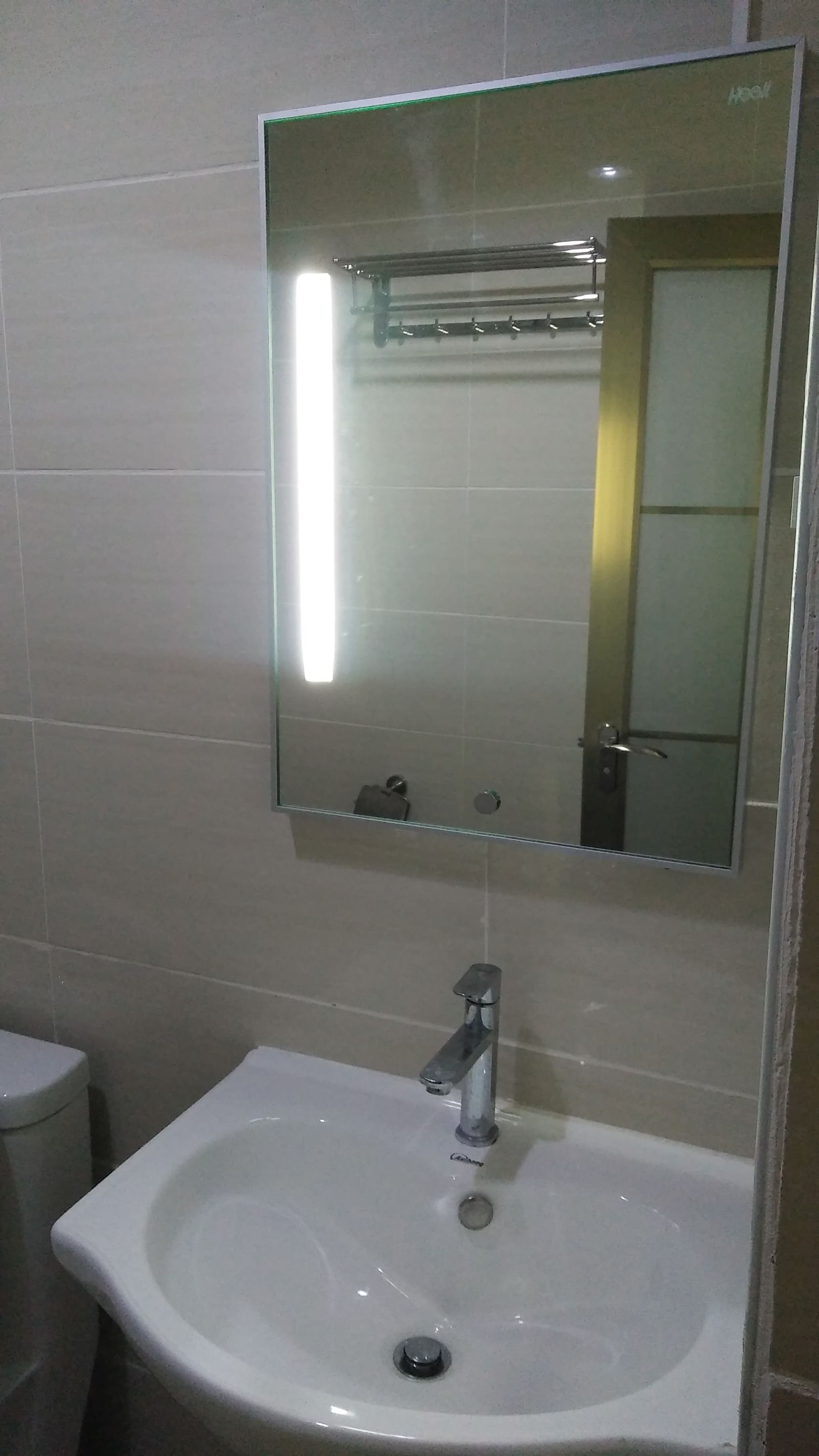 A bathroom with a white sink, a mirror, and a toilet.