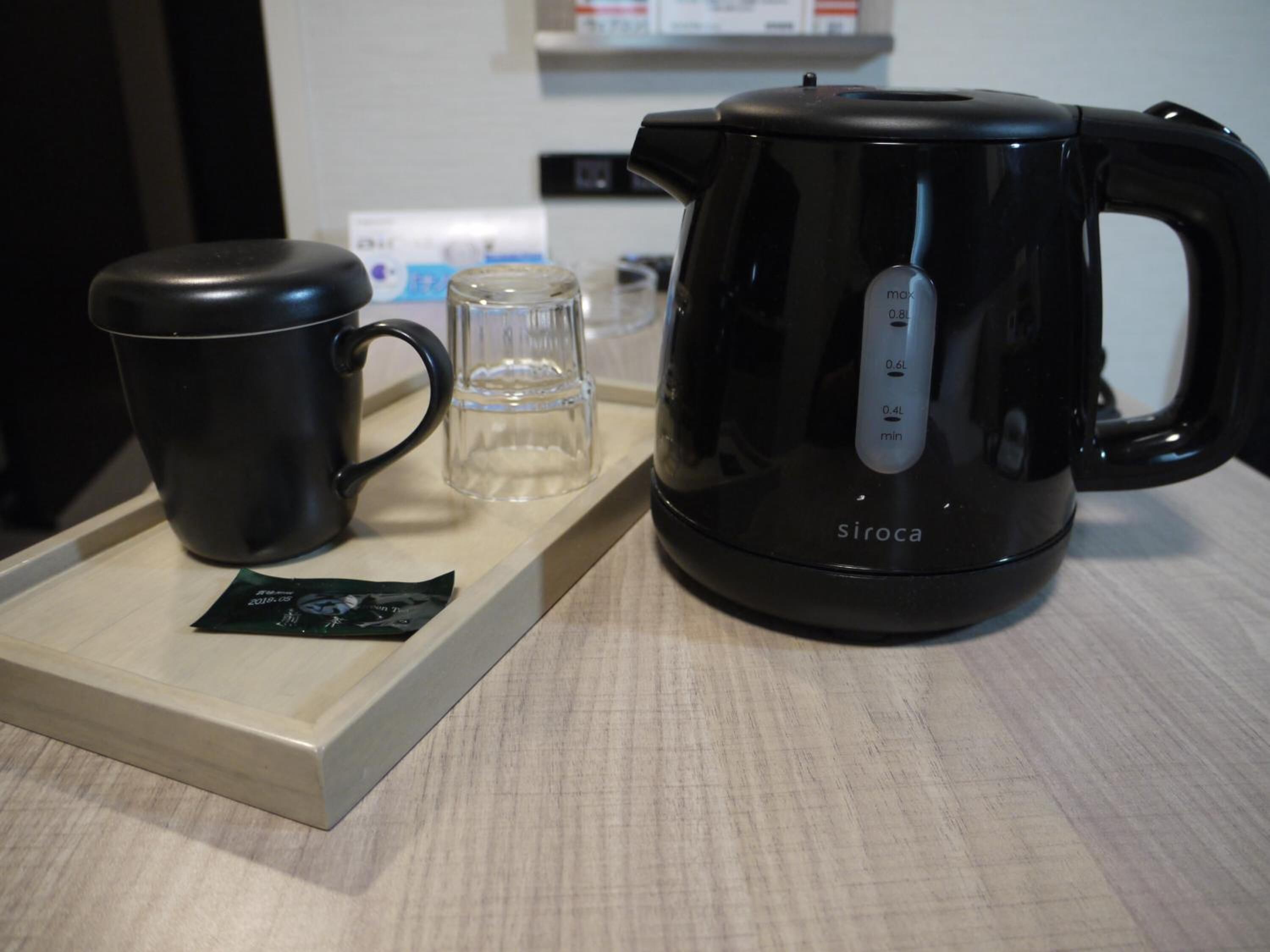Eine schwarze elektrische Wasserwaerme mit digitaler Zeitanzeige auf einer Holztablett.