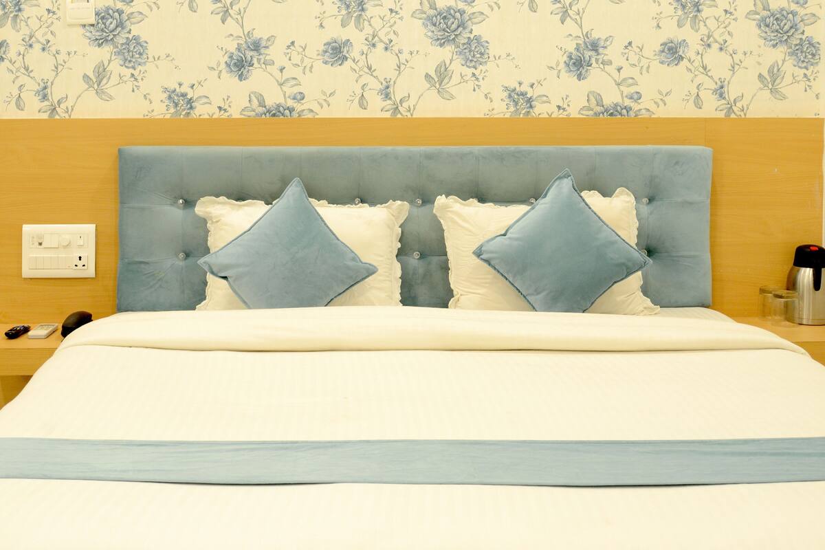 A neatly made bed with a blue headboard, two pillows, and a white bedspread.