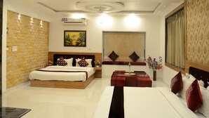 A hotel room with a large bed, a smaller bed, a sofa, a dining table, and a decorative wall. - Ambay Villa (Udaipur)