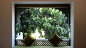 A window with a view of dense foliage and a lattice structure. - Ambay Villa (Udaipur)
