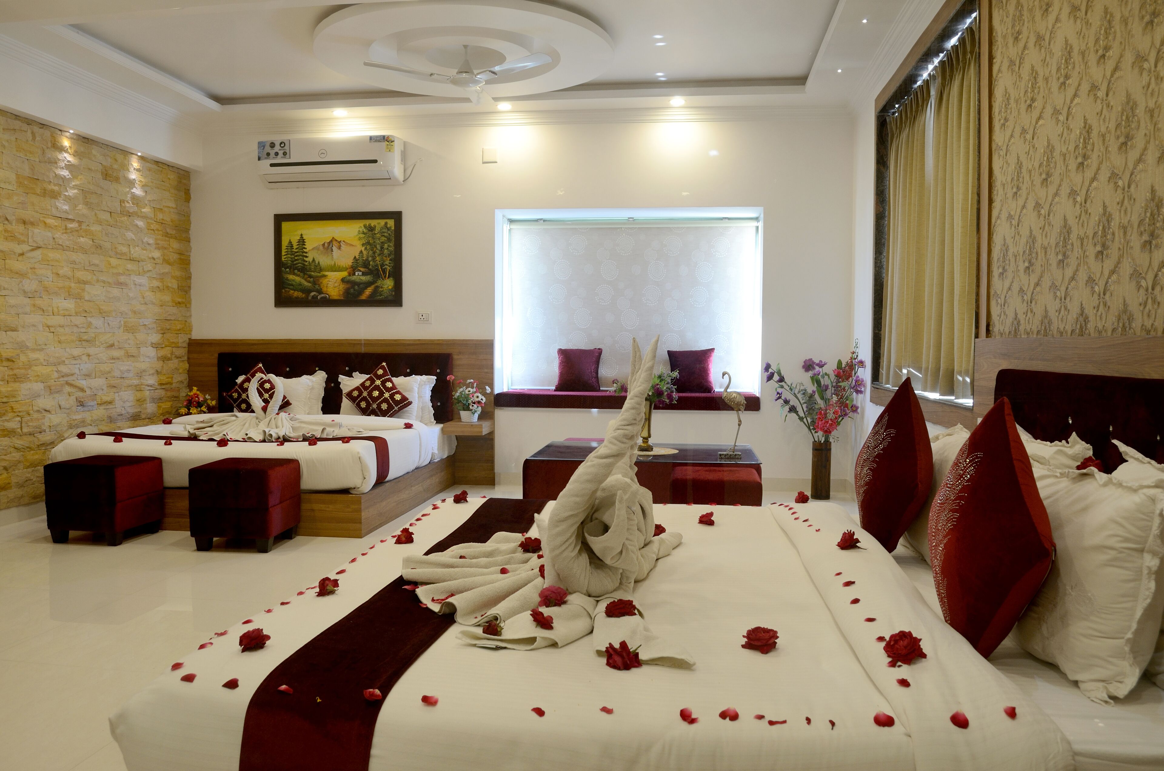 A hotel room with two beds, a large window, a painting on the wall, and a ceiling fan.