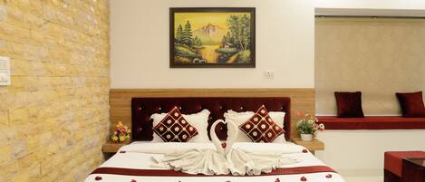 Una habitación de hotel con pared de piedra, cama con ropa de cama roja y blanca, un cuadro de un paisaje y un sofá rojo.